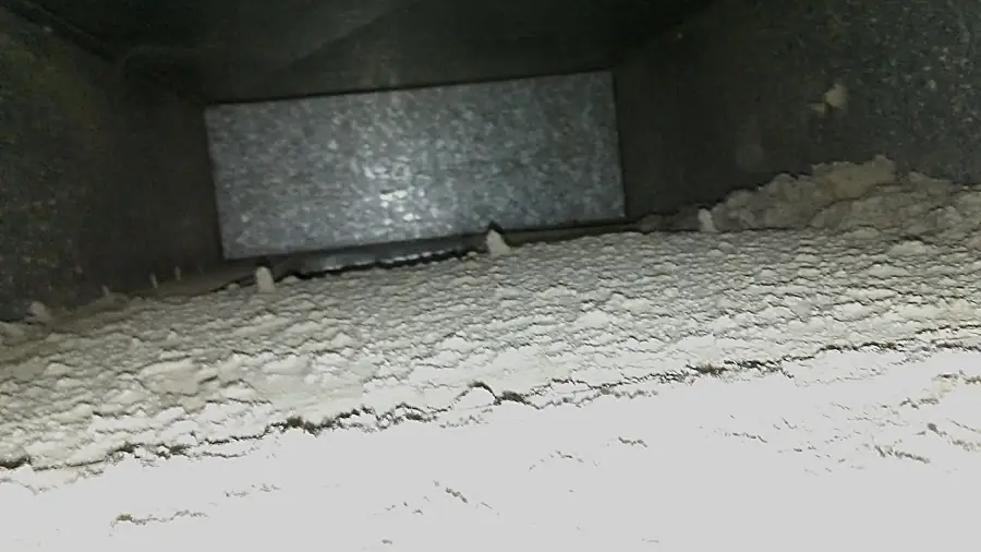The same duct before cleaning: thick layer of dust and debris on the bottom